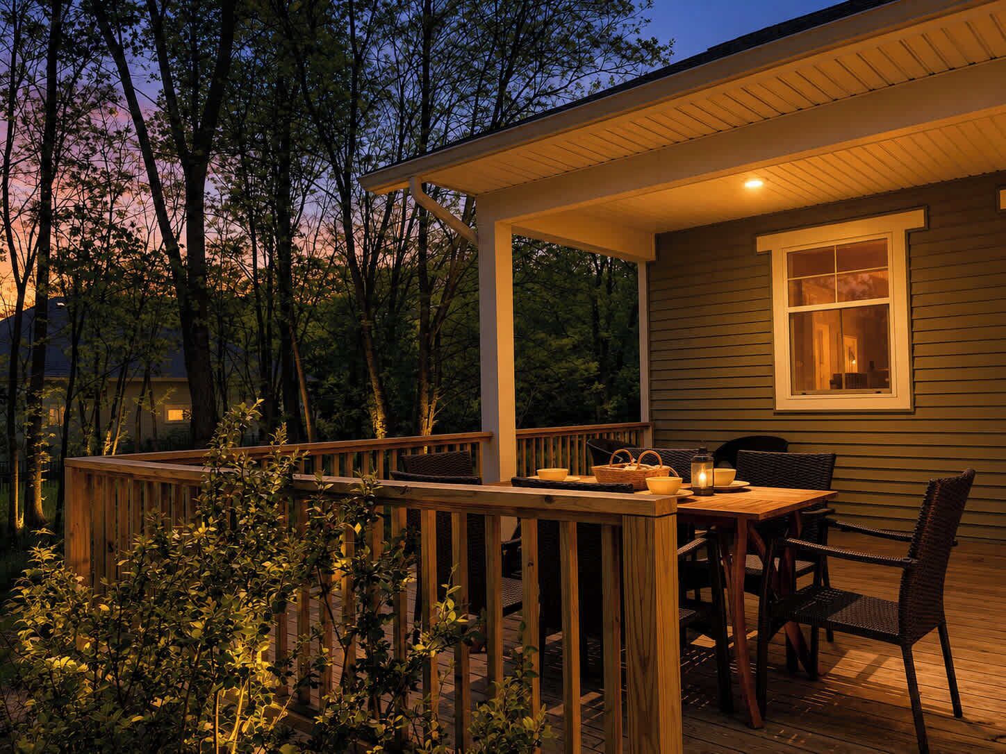 A wooden deck with a table and chairs, a window with a view of trees, and a porch railing.