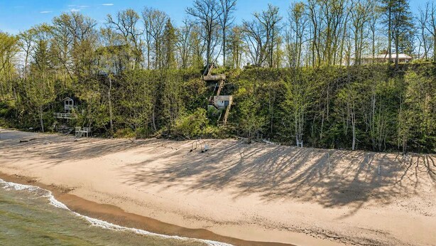 Une plage avec une structure en bois, un petit bâtiment et de nombreux arbres.
