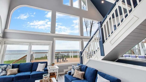 A spacious living area with large windows, a blue sofa, and a view of the ocean.