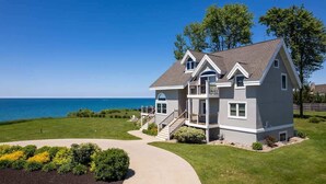 A two-story house with a balcony, a front porch, and a view of the ocean.