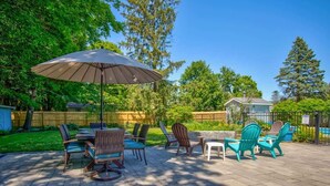An outdoor patio with a dining table, chairs, and a large umbrella. - Woodcliff Cottage | Pool | Bonfire | Coffee Bar (Holland)