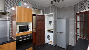 Una cocina compacta con horno integrado, microondas y lavadora.