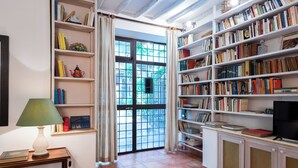 Een kamer met een boekenkast, een televisie en een raam met gordijnen.