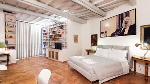 Een slaapkamer met een bed, een bureau, een boekenkast en een televisie.