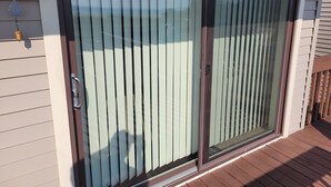 Una puerta corrediza de vidrio con un picaporte metálico, el número '905' en la pared y una pequeña lámpara exterior.