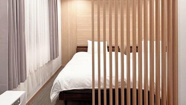 Une chambre d’hôtel moderne avec un lit, des rideaux et une cloison en bois.