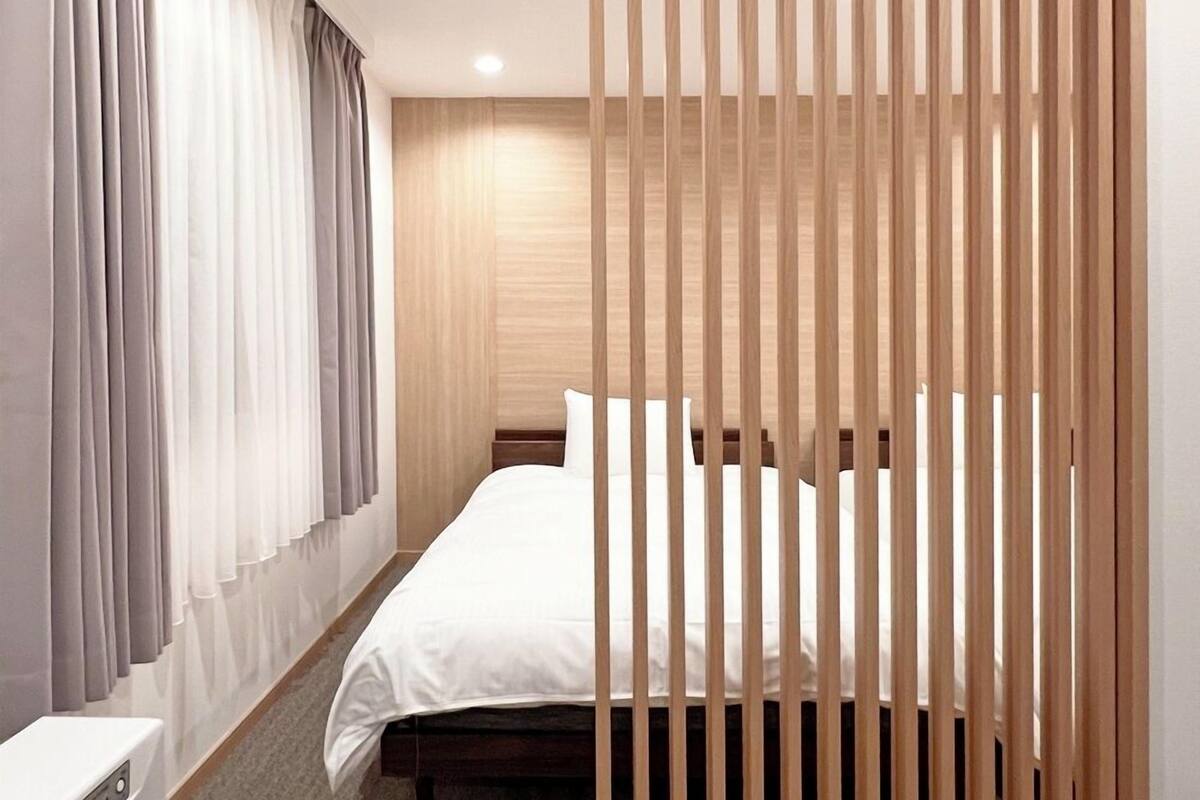A modern hotel room with a bed, curtains, and a wooden partition.
