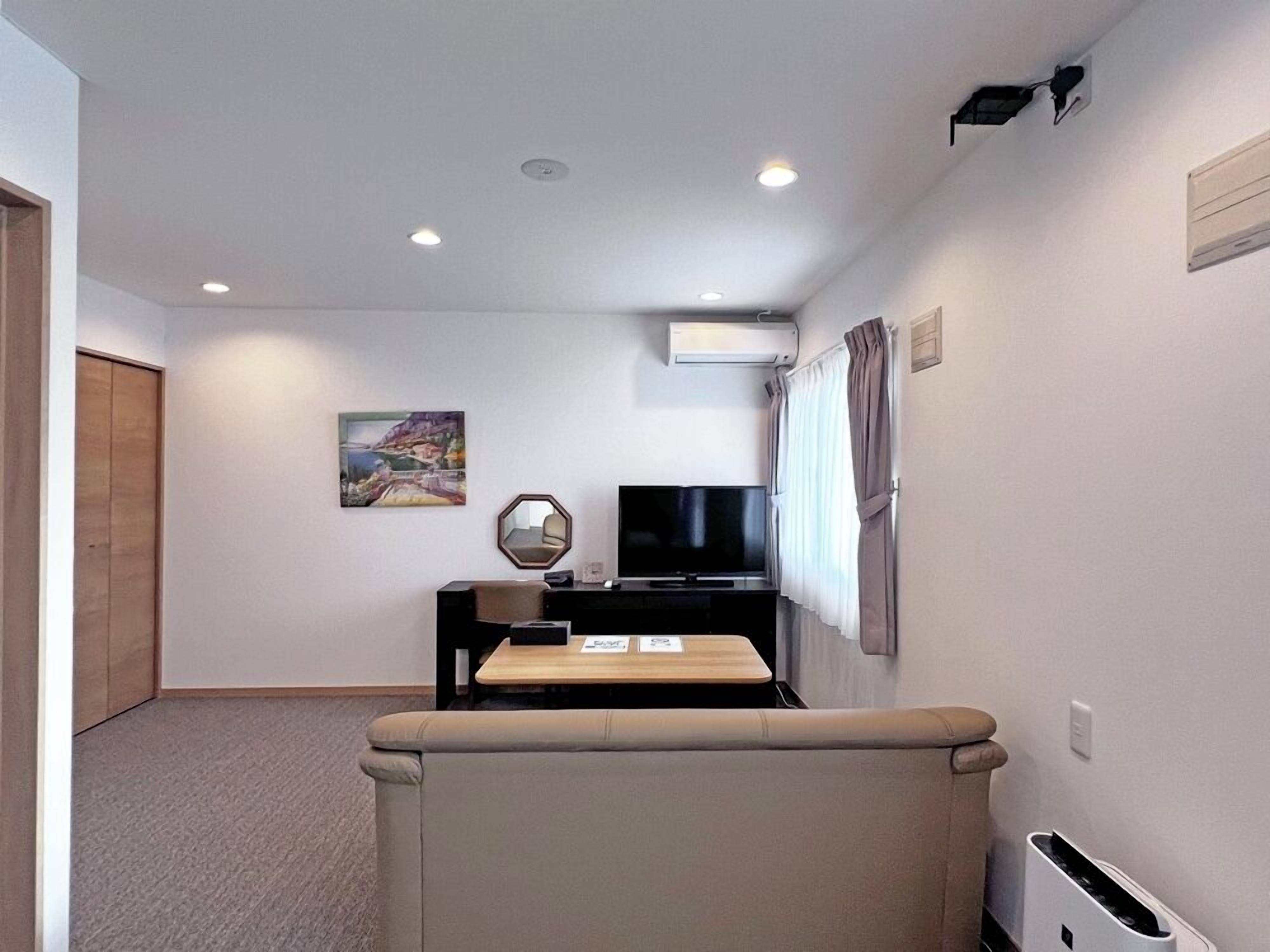 A modern living room with a sofa, a TV, and a painting on the wall.