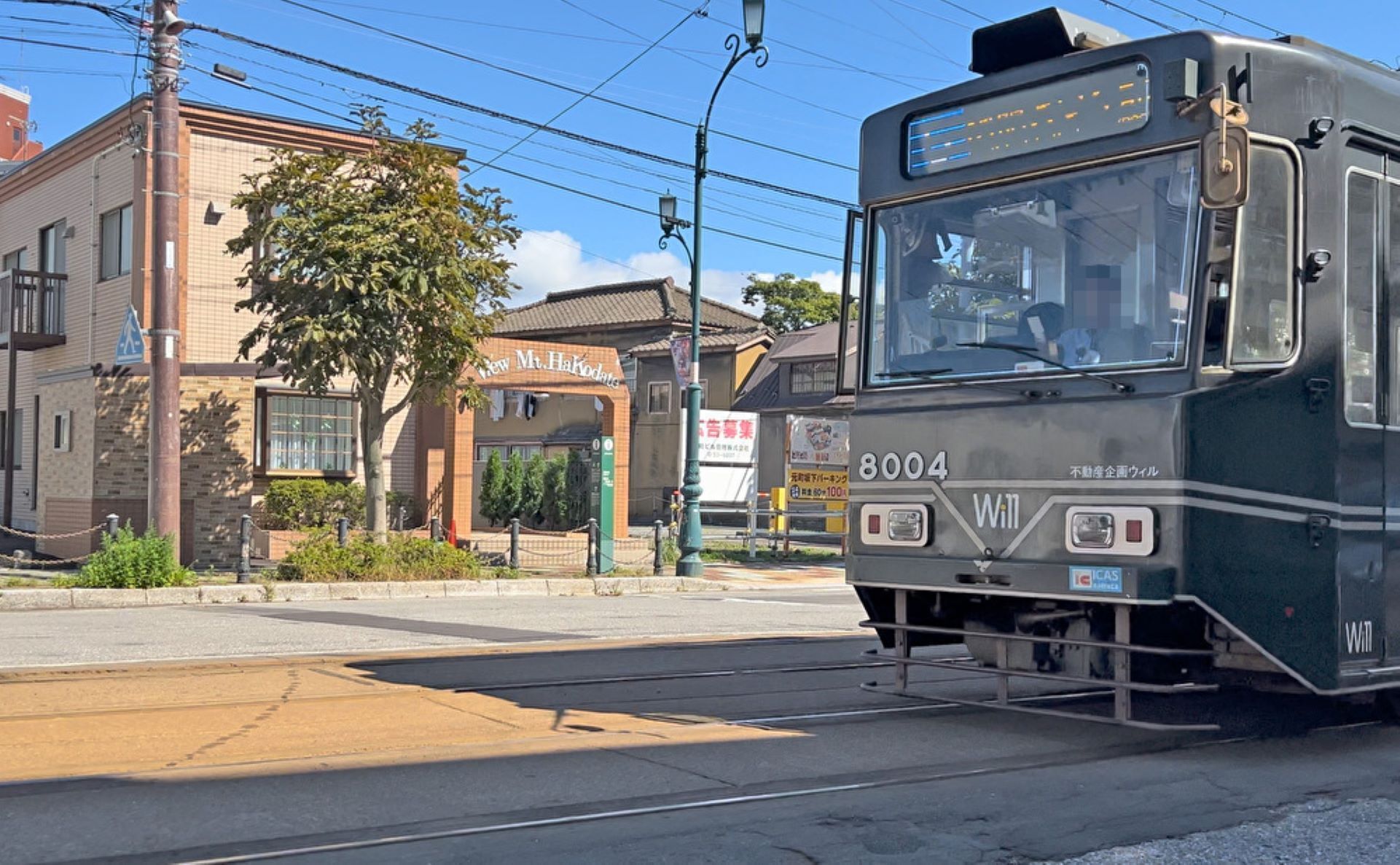 A tram at a station with a brick building in the background.