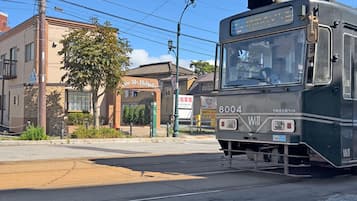 A tram at a station with a brick building in the background.