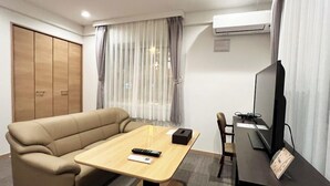 Une chambre d’hôtel moderne équipée d’un canapé, d’une petite table, d’une télévision et d’une armoire.