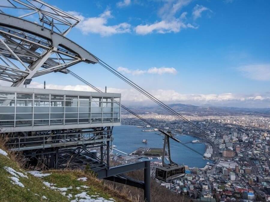 Une station de téléphérique offrant une vue dégagée sur un paysage urbain et sur une étendue d’eau en contrebas.