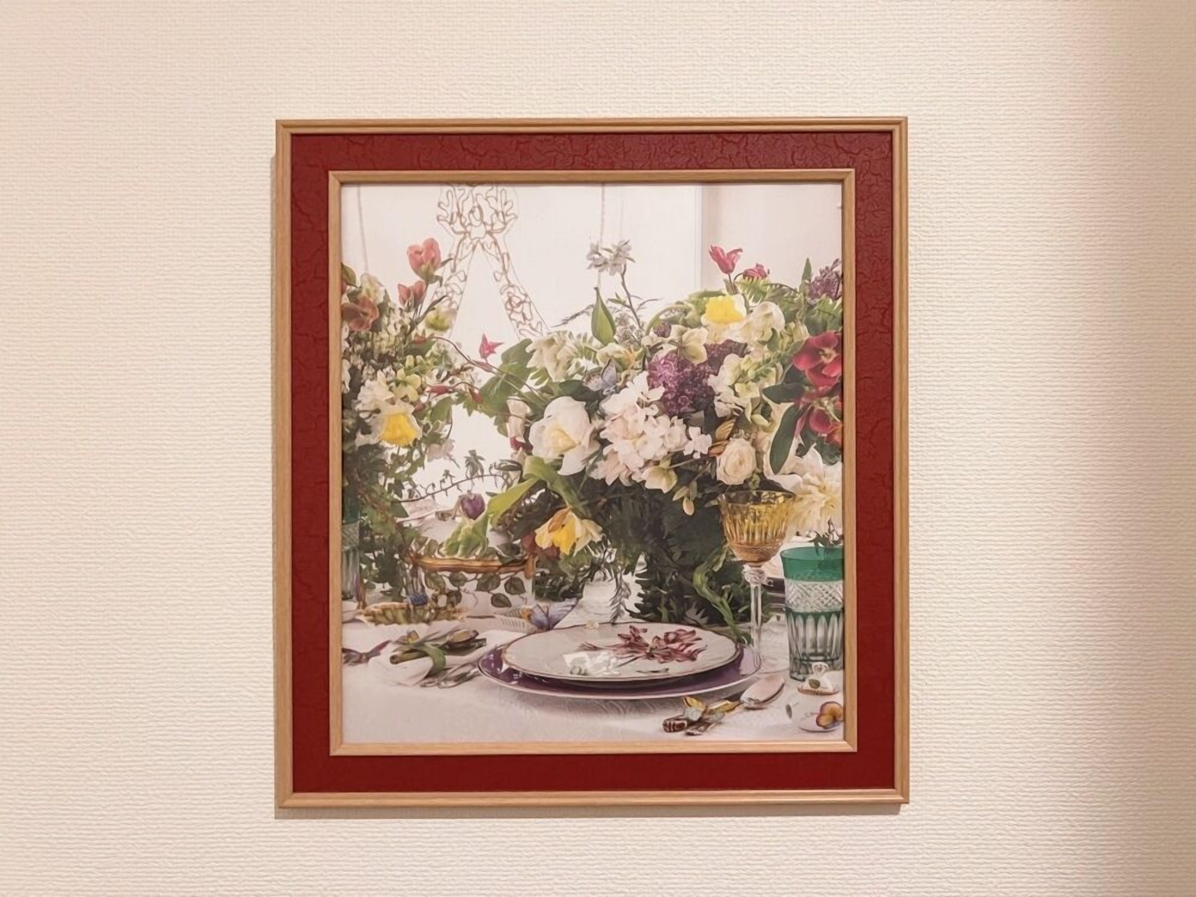 Um quadro emoldurado com um arranjo floral sobre uma mesa.
