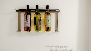 Three wine bottles on a metal rack against a white wall. - Airport bari deluxe  (Bari)