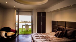 A modern bedroom with a large bed, a chair, a wardrobe, and a balcony with a view of the city. - Airport bari deluxe  (Bari)