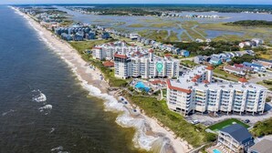 An aerial view of a coastal hotel with multiple buildings, a beach, and a marshy area. - Oceanfront Resort Retreat Stunning Ocean Views (North Topsail Beach)