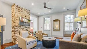 Un salon avec un mur d’accent en briques, deux canapés, une table basse et un téléviseur fixé au mur.