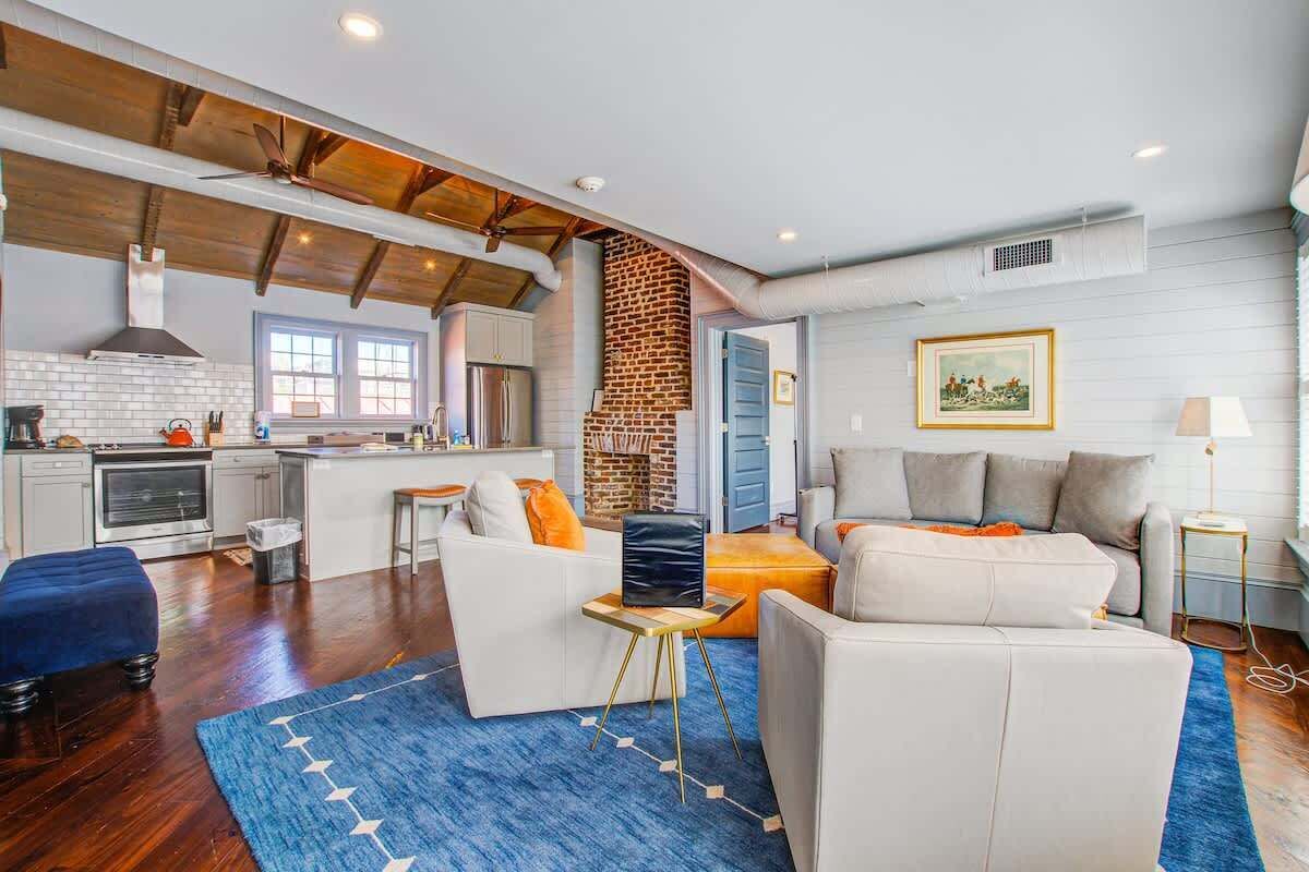 A modern kitchen with white cabinets, a brick wall, and a ceiling fan.