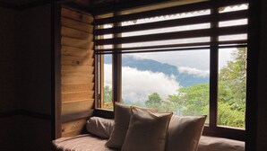 A wooden cabin with a large window overlooking a mountainous landscape. - Art Mile Kalimpong (Kalimpong)