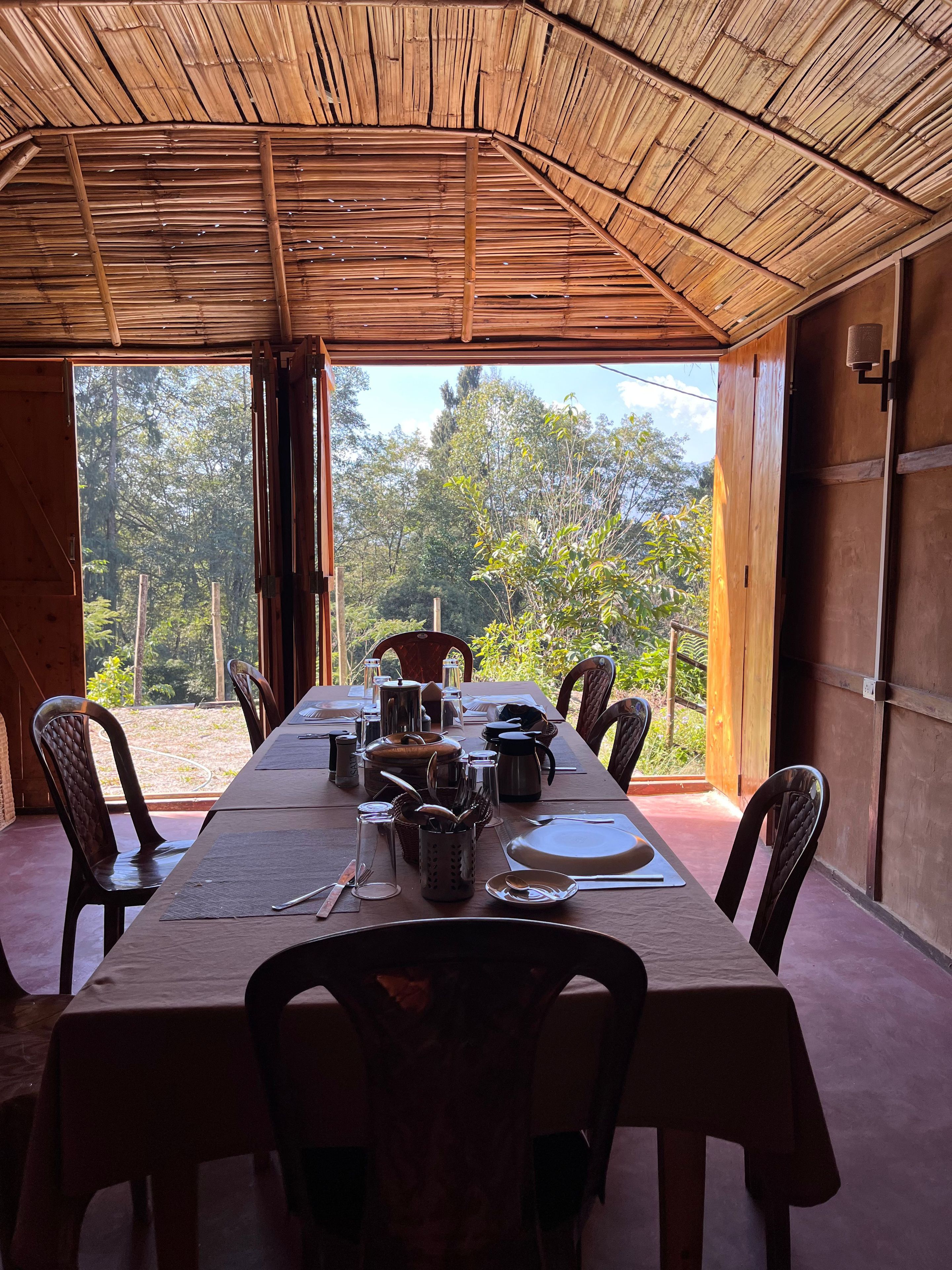 A dining area with a bamboo ceiling, a table set for six, and chairs.