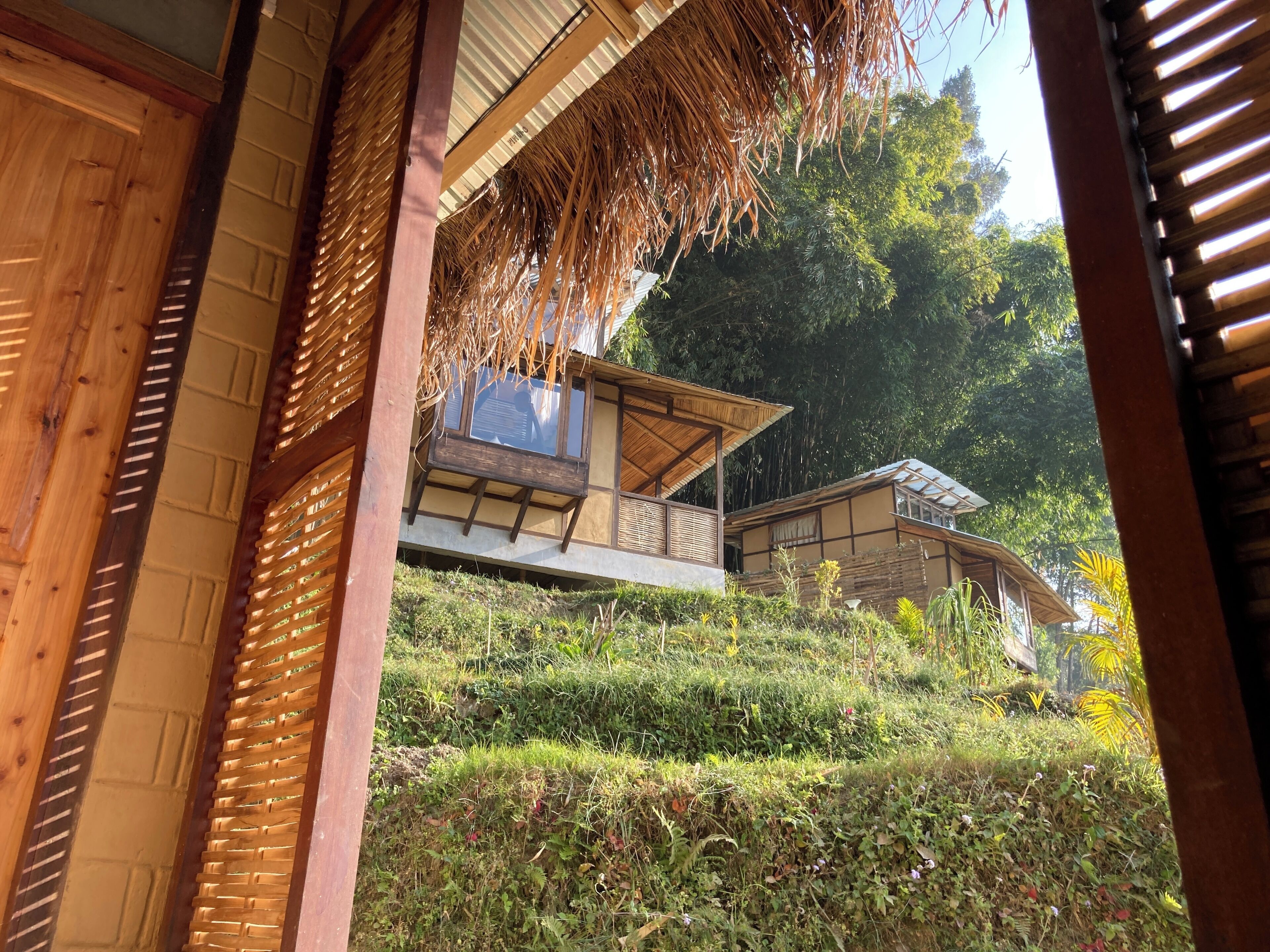 Un edificio de madera tradicional con techo de paja y un balcón con vistas a un jardín exuberante.