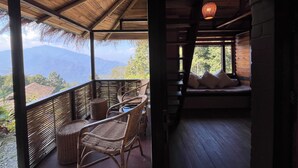 A wooden cabin with a balcony, wicker furniture, and a view of mountains. - Art Mile Kalimpong (Kalimpong)