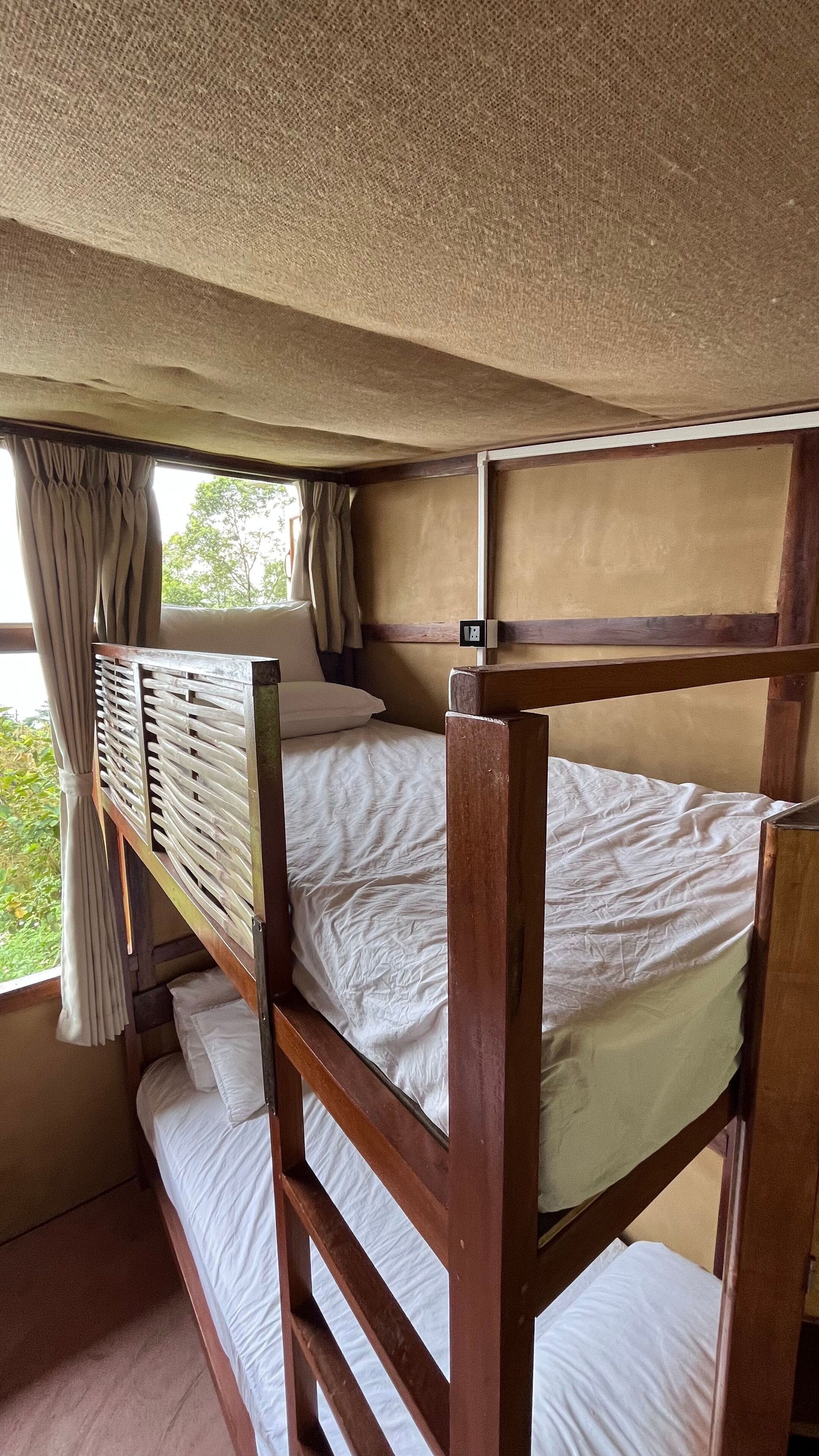 A bunk bed room with a window and curtains.