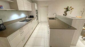 Una cocina moderna con una isla central, horno empotrado y un lavamanos.