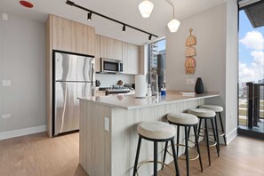 A modern kitchen with a stainless steel refrigerator, a microwave, and a large island with bar stools.