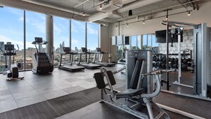 Et rummeligt fitnessrum med løbebånd, styrkemaskiner og et stort spejl.