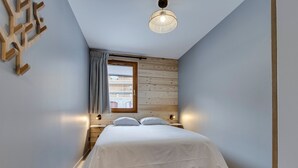 Et soveværelse med seng, træpaneler, et vindue og en loftlampe.