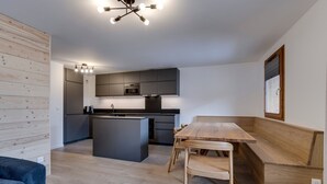 Et moderne køkken med mørke skabe, en central ø og et træspisebord.