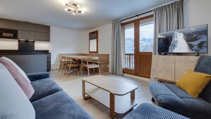 En moderne stue med sofa, sofabord og et spiseområde med stole.