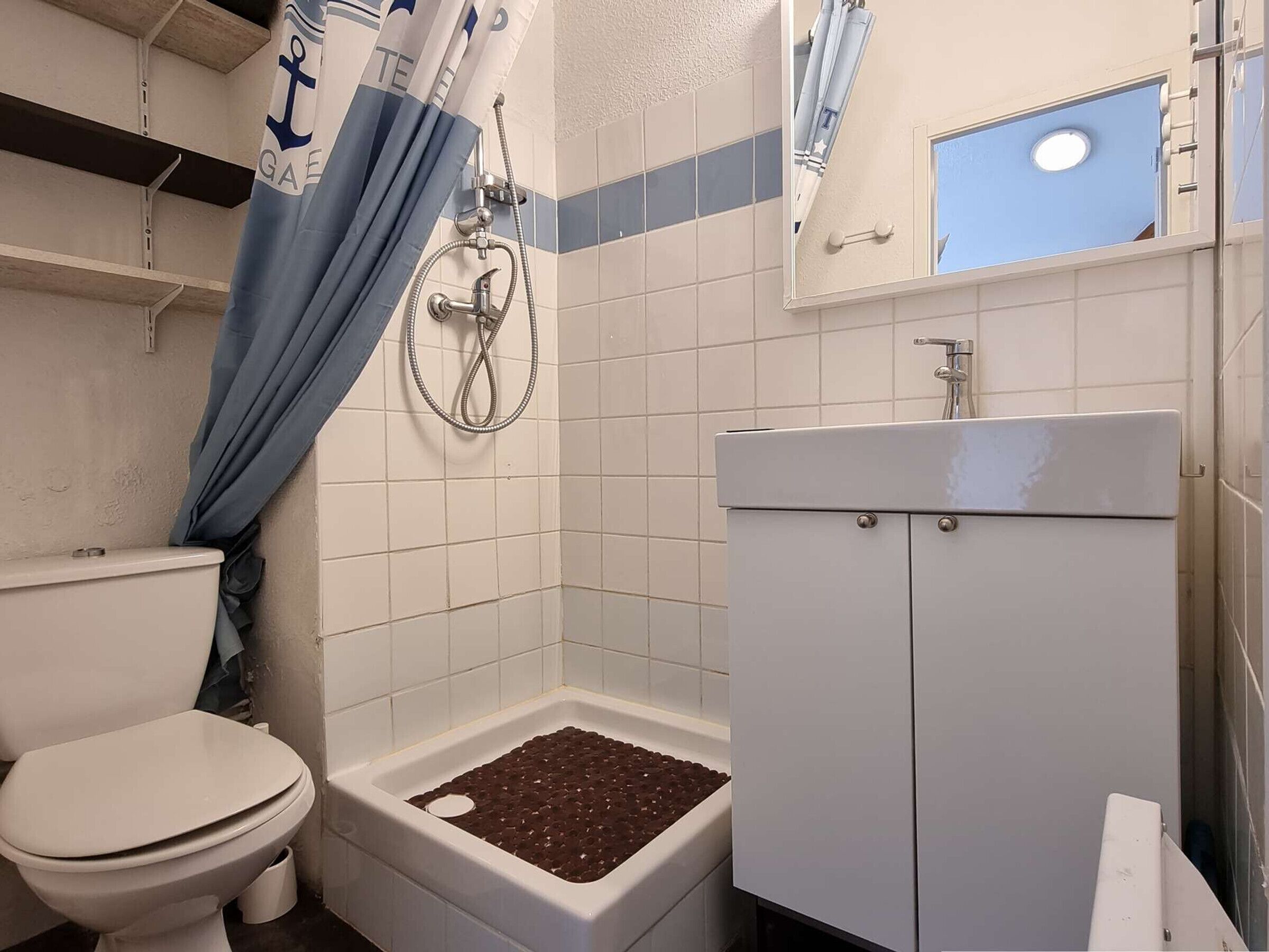 A bathroom with a toilet, a shower with a curtain, and a sink.