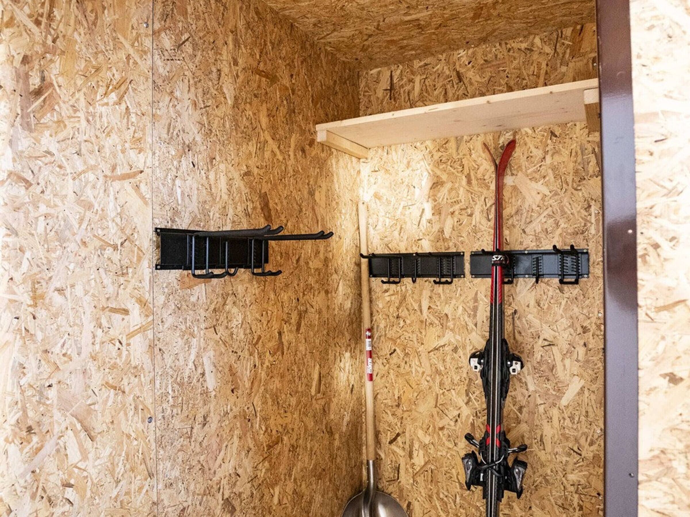 A room with a wooden wall, a metal rack, and a ski pole.