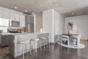 A modern kitchen with a central island, bar stools, and a round dining table.