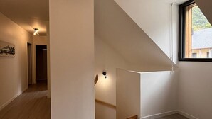 A modern interior with a staircase leading to an upper floor, a hallway, and a window with a view. - Duplex lodge for 8 people, 3 parking spaces, near center (Cauterets)