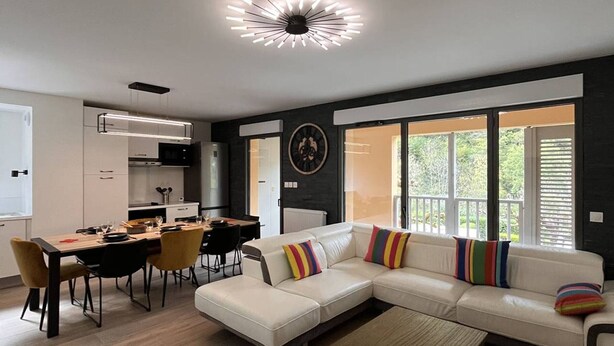 A modern living room with a sectional sofa, dining area, and a kitchen. - Duplex lodge for 8 people, 3 parking spaces, near center (Cauterets)