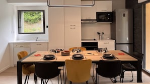 A modern kitchen with a dining area, featuring a wooden table, black and yellow chairs, and stainless steel appliances. - Duplex lodge for 8 people, 3 parking spaces, near center (Cauterets)