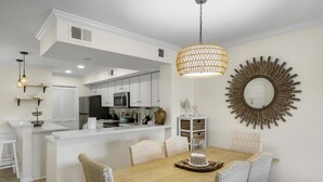 A dining area with a wooden table, wicker chairs, and a decorative centerpiece. - 1BR Lakefront Condo Sandestin w/ Golf Cart (Miramar Beach)