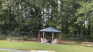 A gazebo with picnic tables and chairs in a park. - Luxurious Brand-New 1BR Apartment – Modern and Open floor plan with fire pit! (Jonesboro)