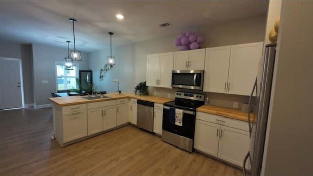 A modern kitchen with white cabinets, stainless steel appliances, and a wooden countertop. - Luxurious Brand-New 1BR Apartment – Modern and Open floor plan with fire pit! (Jonesboro)