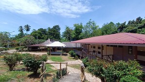 Um edifício com telhado vermelho, rodeado por vegetação e árvores.