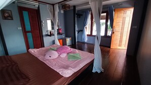 Quarto com cama, mesa de cabeceira, janela com cortinas e porta.