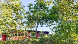 A building with a red exterior and a visible red door, surrounded by dense green foliage. - Cozy home in Strömsnäsbruk with WiFi (Strömsnäsbruk)