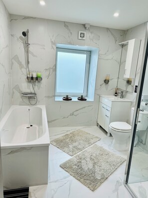Ein modernes Badezimmer mit Badewanne, Toilette und Duschbereich.