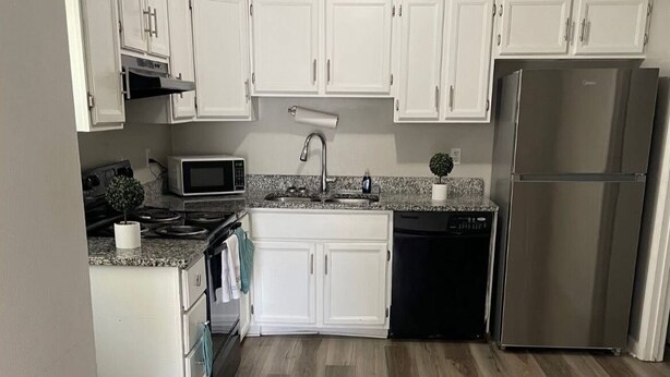 A kitchen with white cabinets, a stainless steel refrigerator, a microwave, a sink, and a dishwasher. - Cozy & Convenient 2BR Corporate Stay – Ideal for Relocation or Recovery (Jonesboro)