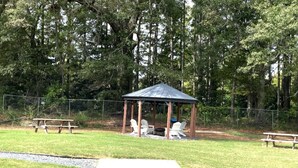A gazebo with a metal roof and wooden pillars, surrounded by a grassy area with picnic tables and chairs. - Cozy & Convenient 2BR Corporate Stay – Ideal for Relocation or Recovery (Jonesboro)