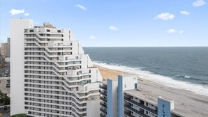 Een meerlaags hotel met balkons met uitzicht op een strand.