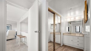Een moderne badkamer met een grote spiegel, houten vloer en een witte wastafelmeubel.